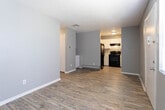 Located at 9960 McCombs St in El Paso, Texas, this single-floor unit offers a practical and functional layout designed for comfortable everyday living. The interior is finished with cool gray walls throughout, creating a cohesive and neutral aesthetic across all rooms.

The entryway opens into a bright living area featuring wood-look laminate flooring and a textured ceiling. Natural light filters in through a window fitted with blinds, while a baseboard heating unit provides warmth. The space flows naturally toward the kitchen area, which is separated by a partial wall that includes a built-in shelving nook and lower cabinetry — a convenient spot for additional storage.

The kitchen is well-appointed with white cabinetry providing ample storage, light-toned countertops, and a full suite of black appliances including a refrigerator, an electric range with coil burners, and an overhead range hood. Wood-look flooring carries through this area, complementing the clean, functional design.

The bedrooms are carpeted for comfort and each features a window with blinds for natural light, baseboard heating, and gray-painted walls. The rooms offer a quiet and cozy atmosphere suited for rest.

The bathroom includes a vanity with white cabinetry and a separate water closet, finished with wood-look flooring that ties back to the rest of the unit. Throughout the space, the design prioritizes functionality and ease of maintenance.