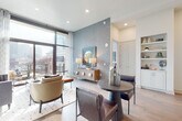 This elegantly designed single-floor residence offers a seamless blend of modern aesthetics and functional living. The open-concept kitchen serves as the heart of the home, showcasing white shaker cabinetry, quartz countertops, a large center island with seating, stainless steel professional-grade appliances including a gas range with hood, and stylish pendant lighting. The kitchen flows naturally into a bright, inviting living area anchored by a textured feature wall and floor-to-ceiling windows that frame dynamic city skyline views and provide access to an outdoor balcony. A dedicated in-unit laundry area adds everyday convenience. The bedrooms are generously proportioned, each bathed in natural light through expansive windows overlooking the urban landscape. The primary suite connects to a spa-inspired en-suite bath featuring a double vanity with dark stone countertops, a soaking tub, and a glass-enclosed walk-in shower, with direct access to a walk-in closet. A second full bathroom mirrors the refined finishes with a glass shower, single vanity, and large-format tile flooring. Throughout the residence, wide-plank hardwood flooring, recessed lighting, and a cohesive neutral palette create a polished, contemporary ambiance ideal for urban living.