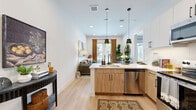 Located at 4700 Fossil Dr in Haltom City, TX, this thoughtfully designed one-bedroom, one-bathroom residence offers a efficient yet comfortable layout across a single floor. The open-concept kitchen and living area forms the heart of the home, featuring light wood cabinetry paired with white upper cabinets, quartz countertops, a peninsula with an undermount sink, stainless steel appliances including a French door refrigerator, electric range, microwave, and dishwasher, all illuminated by modern pendant lighting. Light wood-tone flooring flows throughout, enhancing the bright, airy atmosphere created by white walls and recessed lighting. The living room is anchored by French doors that open to a private outdoor area with views of the community pool and green lawn beyond. The bedroom offers a comfortable retreat with a window overlooking the exterior, providing natural light. The bathroom is appointed with a tub-shower combination featuring matte black fixtures and large-format tile, and connects directly to a dedicated walk-in closet with open rod storage. Clean lines, contemporary finishes, and a cohesive neutral palette define the overall aesthetic of this well-appointed residence.