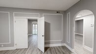 Located at 5345 Cabanne Ave in St. Louis, MO, this 3-bedroom, 1-bathroom residence offers a thoughtfully designed single-floor layout. The unit is finished with light hardwood-style flooring throughout, paired with neutral gray walls and crisp white trim and baseboards, creating a clean, cohesive aesthetic in every room.

The living area makes a strong first impression with an arched entryway, decorative wall molding panels, and an arched front door that adds architectural character. Multiple windows flood the space with natural light and provide views of the surrounding greenery, contributing to an airy, open ambiance.

The galley-style kitchen is well-appointed with gray shaker cabinets, granite-look countertops, a tile backsplash, and black appliances including a gas range and full-size refrigerator. A window above the sink brings in additional natural light.

The primary bedroom is generously sized, featuring an arched window, a standard window, and a sliding glass door that opens to the outdoors. The additional bedrooms are comfortably proportioned, each with closet access and neutral finishes. A central hallway connects the bedrooms to the shared full bathroom, which includes a vanity with a white countertop. The layout is efficient and functional, making excellent use of the available space.