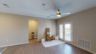 This single-floor residence offers a thoughtfully designed layout with consistent finishes throughout. The open living area serves as the heart of the home, featuring wood-style plank flooring, neutral-toned walls, and a ceiling fan overhead. French doors provide access to an outdoor area, allowing natural light to fill the space. A dedicated hallway leads to additional rooms, maintaining a clear and functional flow.

The kitchen is well-equipped with dark espresso cabinetry, granite countertops, a subway tile backsplash, and stainless steel appliances including a refrigerator, range, and microwave. A peninsula with seating provides additional workspace and casual dining. A dedicated laundry area is conveniently accessible directly from the kitchen.

The bedrooms are generously proportioned, each featuring wood-style flooring, ceiling fans, and windows that bring in natural light and outdoor views. The bathrooms are finished with granite-topped vanities, dark wood cabinetry, tile flooring, and glass-enclosed showers. One bathroom includes a spacious walk-in area adjacent to the shower, adding a sense of comfort and utility. The consistent use of quality finishes throughout creates a cohesive and polished atmosphere.