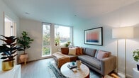 Located in Portland's vibrant West End neighborhood, this thoughtfully designed single-floor residence offers a seamless blend of modern aesthetics and functional living. The open-concept living area is anchored by large corner windows that frame views of the surrounding cityscape, flooding the space with natural light and creating an airy, welcoming atmosphere. Light hardwood-style flooring flows throughout, tying the rooms together cohesively.

The kitchen is a standout feature, outfitted with dark cabinetry, crisp white countertops, stainless steel appliances including a gas range and French door refrigerator, and a distinctive hexagonal tile backsplash. A peninsula with bar seating provides both additional prep space and a casual dining option. A separate dining area accommodates a full table, ideal for entertaining.

The bedroom offers a cozy yet well-appointed retreat, featuring a large window that draws in natural light, exposed concrete accents, a sliding closet, and stylish patterned wallcovering that adds character. The bathroom is finished with full-height white subway tile surrounding a soaking tub, complemented by a bold accent wall that adds a pop of color. Throughout the residence, clean lines and contemporary finishes create a polished, inviting living environment.