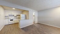 Located at 127 S Colby Ave in Valley Center, Kansas, this single-floor studio unit offers an efficient and functional layout designed to maximize every square foot. The combined kitchen and living area forms the heart of the space, where wood-look plank flooring runs throughout, providing a warm and cohesive aesthetic. Neutral gray walls and white trim contribute to a clean, understated interior palette.

The kitchen is well-equipped with white cabinetry offering ample upper and lower storage, laminate countertops, a white electric range, a built-in sink, and a full-size refrigerator. A pass-through opening connects the kitchen to the living area, enhancing the sense of openness. A wall-mounted HVAC unit ensures year-round climate control, and a window along one wall brings in natural light.

The living area provides a versatile open space with a textured popcorn ceiling and a centrally located entry door. The bathroom features a tub-shower combination with crisp white surrounds. Throughout the unit, the clean finishes and straightforward design create a practical, move-in-ready environment suited for efficient single-occupancy living.