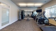 Located at 1649 SR-12 N in Ashland City, Tennessee, this fitness center is a single-floor facility designed to support a comprehensive workout experience. The space features a clean, modern aesthetic with neutral-toned walls, patterned carpet tile flooring, and flush-mounted rectangular lighting panels that provide consistent, even illumination throughout.

The cardio section is well-stocked with Matrix-brand equipment, including elliptical trainers, stair climbers, treadmills, and a stationary cycle, several of which are equipped with individual digital display consoles. Wall-mounted flat-screen televisions are positioned for easy viewing during workouts, and large windows along one wall allow natural light to enter while offering views of the surrounding exterior.

The strength training area includes a Matrix functional trainer cable machine, a selectorized strength station, a rack of rubber-coated dumbbells in graduated sizes, and a selection of medicine balls and weighted accessories. Together, these stations accommodate both machine-based and free-weight training.

Entry to the fitness center is through glass-panel double doors, connecting to an adjacent interior corridor. The space also includes a wall clock, waste receptacle, and posted fitness guidelines, contributing to an organized and user-friendly environment overall.