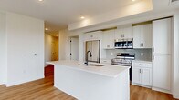 Located at 11816 Wayzata Blvd in Minnetonka, MN, this thoughtfully designed 2-bedroom, 2-bathroom residence offers a clean, modern aesthetic throughout its single-floor layout. The open-concept living, dining, and kitchen area serves as the heart of the home, featuring warm light wood-tone flooring that flows seamlessly throughout the main living spaces. The kitchen is a standout, boasting white shaker cabinetry with matte black hardware, a large center island with a white quartz countertop and undermount sink, subway tile backsplash, and a full suite of stainless steel appliances including a refrigerator, electric range, microwave, and dishwasher. The primary bedroom is a well-proportioned retreat with its own closet space and light wood flooring, while the second bedroom offers plush carpeting and a large black-framed window with outdoor views. Both bedrooms feature ample closet storage, complemented by five closets throughout the unit. The two bathrooms maintain the home's crisp design language with white cabinetry, quartz countertops, black-framed mirrors, and light wood-tone flooring. The primary bath includes a tiled walk-in shower with a black-framed glass door. Clean white walls and recessed lighting complete the bright, contemporary feel of this well-appointed residence.