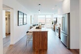 Located at 707 South Worth Street in the heart of Birmingham, Michigan, this contemporary 2-bedroom, 4-bathroom residence offers a thoughtfully designed single-level layout with high-end finishes throughout. The open-concept kitchen and living area serves as the centerpiece of the home, anchored by a walnut-accented island with a quartz waterfall countertop, an undermount sink, stainless steel appliances including a full-size refrigerator and professional-grade range, and sleek white upper cabinetry extending to the ceiling. The adjacent living room is flooded with natural light through expansive floor-to-ceiling windows and offers direct access to an outdoor balcony with views of downtown Birmingham. Wide-plank hardwood floors flow seamlessly throughout the space, enhancing its clean, modern aesthetic. The generously sized primary bedroom features large windows framing outdoor city views, a dedicated walk-in closet with custom built-in shelving, and an en-suite bathroom appointed with a dual-sink walnut vanity and a glass-enclosed tiled walk-in shower. Additional bedrooms and bathrooms maintain the same level of refined finishes. A dedicated laundry room with Whirlpool washer and dryer, overhead cabinetry, and a countertop workspace adds practical convenience to this polished urban residence.