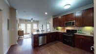 This single-floor residence offers a thoughtfully designed open-concept layout that seamlessly connects the kitchen, dining, and living areas. The kitchen is a standout feature, showcasing rich dark mahogany cabinetry, granite countertops, a classic white subway tile backsplash, and a full suite of stainless steel appliances including a gas range, built-in microwave, dishwasher, and refrigerator. A peninsula with bar seating provides additional prep space and a natural gathering point. Crown molding accents the main living areas, while warm hardwood flooring runs throughout the entire unit, lending a cohesive and elegant feel.

The living room is bright and inviting, benefiting from large French doors that allow natural light to pour in and provide access to an outdoor area. A ceiling fan contributes to comfort and airflow. Both bedrooms are generously proportioned, each featuring French doors with transom windows above, ceiling fans, and the same rich hardwood flooring.

The bathrooms are finished with large-format tile flooring, dark wood vanities with granite countertops, and subway tile surrounds. The primary bathroom includes a soaking tub and direct access to a walk-in closet, offering added convenience and storage. Overall, the space presents a clean, modern aesthetic with warm, classic design elements throughout.