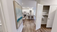 This well-appointed 3-bedroom, 2-bathroom single-story home in Knoxville, Tennessee offers a thoughtfully designed open-concept layout. The combined kitchen, dining, and living area forms the heart of the home, featuring rich wood-tone flooring throughout. The kitchen is outfitted with crisp white shaker cabinets, a subway tile backsplash, stainless steel appliances, gray quartz countertops, and a central island with bar seating — ideal for both cooking and casual entertaining. An adjacent walk-in pantry provides generous storage. The dining area accommodates a full table and is accented with crown molding, while the living room offers access to an outdoor area through glass doors, flooding the space with natural light. A ceiling fan completes the relaxed atmosphere. All three bedrooms feature plush carpet flooring, ceiling fans, and large windows. The spacious primary bedroom includes a walk-in closet with wire shelving. The bathrooms offer clean, functional designs including a walk-in shower with gold-tone fixtures. A dedicated laundry room houses a full-size washer and dryer. Crown molding and neutral tones throughout lend a polished, cohesive aesthetic to this comfortable Knoxville residence.