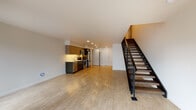 Located at 701 5th Avenue North in Seattle's vibrant South Lake Union neighborhood, this two-story residence offers a thoughtfully designed layout with modern finishes throughout. The main level features an open-concept living and dining area bathed in natural light from multiple large windows fitted with roller shades, offering views of the surrounding neighborhood. Light hardwood flooring flows seamlessly across the main level, enhancing the bright, airy ambiance. A sleek, contemporary kitchen anchors the space, outfitted with dark wood cabinetry, subway tile backsplash, light stone countertops, and a full suite of stainless steel appliances including a French door refrigerator, electric range, microwave, and dishwasher. A striking open-riser staircase with a black metal railing connects the two floors. The upper level hosts a carpeted bedroom with a wall-mounted mini-split HVAC unit, alongside a well-appointed bathroom featuring warm wood vanity cabinetry, a quartz countertop, large mirror, and a soaking tub with shower. In-unit stacked Whirlpool washer and dryer add everyday convenience. Clean white walls and recessed lighting throughout give the entire space a polished, contemporary feel.