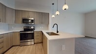 Located at 19279 NW 27th Ave in Miami Gardens, Florida, this well-appointed 2-bedroom, 2-bathroom residence offers a thoughtfully designed single-level layout with modern finishes throughout. The open-concept living area is anchored by durable wood-look luxury vinyl flooring that flows seamlessly through the main living spaces, creating a warm and cohesive aesthetic.

The kitchen is a standout feature, showcasing light wood-grain cabinetry, stainless steel appliances including a refrigerator, range, and built-in microwave, and a white quartz peninsula with an undermount sink and a sleek matte black faucet. Stylish pendant lighting adds a contemporary touch above the peninsula, which opens directly to the spacious living area.

Both bedrooms are generously sized, each featuring large windows with roller shades that invite natural light while providing privacy. The primary bedroom connects to an en-suite bathroom equipped with a wood-tone vanity, white quartz countertop, walk-in glass shower, and elegant tile flooring. A walk-in closet adjoins the primary bath. The second bathroom mirrors the same modern design with a single vanity and lighted mirror. Sliding glass doors in the main living area open to a private balcony with tropical palm tree views.