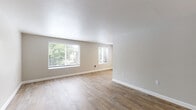 Located at 19839 S Hwy 213 in Oregon City, Oregon, this single-floor unit offers a clean, modern interior with a neutral color palette and a variety of thoughtful finishes throughout. The open living area features light-toned wood-style flooring, textured ceilings, and multiple windows fitted with horizontal blinds that invite abundant natural light and views of surrounding greenery. A wall-mounted heater provides efficient climate control in the main living space. The galley-style kitchen is well-appointed with gray shaker cabinetry, marble-look countertops, a stainless steel sink, and black appliances including a range and refrigerator, all set atop light hardwood-style flooring. The bedrooms are carpeted for comfort and include generous closet space with sliding doors. One bedroom features a sliding glass door that opens to a private balcony, offering a pleasant outdoor retreat. An additional room with wood-style flooring and a wall-access door provides flexible use. The bathroom includes a marble-look vanity with an undermount sink, a bathtub with shower, and wood-look tile flooring accented by a brushed nickel grab bar. Throughout the unit, clean white trim and neutral gray-beige walls create a cohesive, move-in-ready atmosphere.