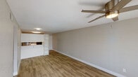 This single-floor residence offers a thoughtfully laid-out interior finished in a clean, neutral color palette throughout. The open living and dining area is anchored by light wood-look flooring that runs seamlessly across the space, complemented by a ceiling fan with integrated lighting. Natural light filters in through a window fitted with blinds near the entry door, creating a bright and welcoming atmosphere.

The galley-style kitchen is efficiently designed, featuring white shaker-style cabinetry, stainless steel appliances including a refrigerator and electric range, a single-basin sink, and a subtle subway tile backsplash. Light wood-look flooring continues here, tying the kitchen visually to the main living area. A pass-through opening with built-in white shelving connects the kitchen to the living space, adding both functionality and an open feel.

The two bedrooms are finished with plush wall-to-wall carpeting and are each equipped with ceiling fans. Both rooms are generously proportioned with clean, neutral walls and good natural light from windows dressed with blinds.

The bathroom is compact and functional, offering a full tub-shower combination, a white vanity with cabinetry, a toilet, and wood-look tile flooring. The overall design of this residence prioritizes practicality, cohesion, and comfort throughout.
