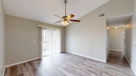 Located at 2231 Cascades Blvd in Kissimmee, Florida, this two-bedroom residence offers a well-organized, single-floor layout with a clean, contemporary aesthetic throughout. Light-toned wood-look flooring runs consistently across all rooms, lending a cohesive and modern feel to the space.

The open living room is a standout area, featuring vaulted ceilings, a ceiling fan with light fixture, and a full-width sliding glass door that opens to a private balcony, allowing abundant natural light and outdoor views to fill the room. The kitchen is efficiently designed in a galley configuration, showcasing white cabinetry with matte black hardware, light stone-finish countertops, and black appliances including an electric range, refrigerator, and dishwasher. A dedicated dining area adjacent to the kitchen features its own ceiling fan.

The primary bedroom is generously sized and includes a closet and direct access to a private bathroom equipped with a vanity and overhead lighting. The second bedroom is bright and comfortable, with a window offering views of surrounding greenery. A dedicated in-unit laundry room accommodates a full-sized washer and dryer side by side. Neutral wall tones and textured ceilings complete the understated, functional design of this Kissimmee residence.