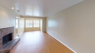 This single-floor unit offers a functional and well-appointed layout across several distinct areas. The open living and dining space is finished with warm wood-look laminate flooring and neutral-toned walls, allowing natural light to flow in through large windows. A textured ceiling adds subtle character throughout the main living areas.

The galley-style kitchen is efficiently designed, featuring rich dark wood cabinetry paired with light granite-look countertops. Black appliances, including a range and refrigerator, complement the cabinetry, while additional storage is provided by upper and lower cabinets lining both sides of the kitchen. Light wood-look flooring continues into this space, and a door at the end of the kitchen provides convenient access.

The bedrooms are carpeted in a neutral tone and each include a ceiling fan with integrated lighting, offering comfort and practicality. Windows in the bedrooms bring in natural light and provide views to the exterior.

The bathroom is clean and well-equipped, featuring a single-basin vanity with a granite-look countertop set into dark wood cabinetry, a large mirror with overhead lighting, and a full-size soaking tub and shower combination enclosed by classic white square tile. The overall design of the unit is practical and cohesive, with consistent neutral tones and functional finishes throughout.