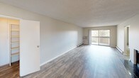 This single-floor residence offers a well-organized layout across several distinct living areas. The galley-style kitchen is outfitted with white shaker cabinetry, light stone countertops, a stainless steel refrigerator, built-in microwave, electric range, and dishwasher, all set above durable wood-look flooring that extends into the main living areas.

The spacious living room features the same wood-look flooring, neutral wall tones, a textured ceiling, and a sliding glass door that opens to a private balcony, filling the space with natural light and outdoor views. A fireplace is also visible in the floor plan, serving as a focal point for the living area.

Bedrooms are carpeted for comfort and include sliding-door closets with built-in shelving and hanging rods. Windows fitted with horizontal blinds allow for adjustable natural light, and baseboard heating is present throughout.

Two bathrooms serve the unit. One features a walk-in shower with gold ceramic tile surround, a sliding glass enclosure, a wide vanity with dual sinks, and a large mirror with overhead lighting. The second bathroom offers a full soaking tub with a matching gold tile surround. Both bathrooms include wood-look tile flooring.
