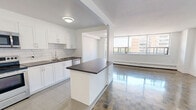 Located at 25 Cougar Crt in Toronto's Scarborough neighbourhood, this well-appointed one-bedroom, one-bathroom unit offers a comfortable and functional layout across a single floor. The living room is a standout space, featuring classic parquet flooring and a wall of large windows that flood the room with natural light while offering pleasant outdoor views of the surrounding neighbourhood. A baseboard heating system runs along the window wall, ensuring year-round comfort.

The kitchen has been updated with crisp white shaker-style cabinetry, a white subway tile backsplash, dark countertops, and stainless steel appliances including a refrigerator, stove, and microwave. Light tile flooring and ample cabinetry make this a practical and clean workspace. A peninsula counter separates the kitchen from the living area, enhancing the open feel.

The generously sized primary bedroom continues the parquet flooring and features mirrored sliding closet doors, adding depth and light to the space. The bathroom is finished with full-height white subway tile surrounding a soaking bathtub, lending a clean, classic aesthetic. Bright white walls and neutral finishes throughout give the entire unit a fresh, move-in-ready feel.