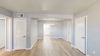This single-story, 3-bedroom, 1-bathroom home offers a thoughtfully laid-out floor plan designed for comfortable everyday living. Consistent light wood laminate flooring and soft gray-toned walls flow throughout, creating a cohesive and modern aesthetic. The open living and dining area is anchored by a stylish chandelier and connects seamlessly to the kitchen through a wide archway. The kitchen features white shaker-style cabinetry with sleek bar-pull hardware, marble-look quartz countertops, a matching backsplash, and a dishwasher — delivering a clean, contemporary feel. The spacious primary bedroom benefits from dual windows fitted with blinds and a ceiling fan with light fixture, filling the room with natural light and ensuring comfortable airflow. The two additional bedrooms are well-sized, each equipped with ceiling fans and generous window coverage, offering ample natural light and outdoor views. The bathroom includes a full tub-shower combination with white subway tile surround and a window for natural ventilation. A hallway with a multi-bulb chandelier connects the bedrooms and adds a welcoming brightness to the interior. Throughout, white trim and baseboards provide crisp contrast against the neutral walls, completing the home's clean and move-in-ready presentation.