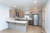 Located at 6328 W State St in Boise, Idaho, this contemporary three-story home showcases modern design with clean lines and quality finishes throughout. The interior is characterized by crisp white walls, light-toned luxury vinyl plank flooring on the main level, and plush carpeting in the upper-floor rooms, creating a cohesive and inviting aesthetic.

The kitchen serves as a central highlight, featuring light wood cabinetry with matte black hardware, white quartz countertops, a subway tile backsplash, and a full suite of stainless steel appliances including a gas range, dishwasher, and French door refrigerator. A wall-mounted range hood and a central island with seating add both function and style.

The bathrooms are tastefully finished with light wood vanities, white quartz surfaces, stone tile flooring, and matte black fixtures. The primary bathroom includes a dual-sink vanity, a sliding barn door, and an adjacent walk-in closet, while a secondary bath offers a tiled tub-shower combination.

Carpeted bedrooms provide natural light through well-placed windows. A dedicated laundry room with a full-size Whirlpool washer and dryer adds everyday convenience. Carpeted stairs connect all three floors of this thoughtfully designed Boise home.