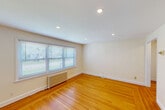 Located at 41 Garden City Dr in Cranston, Rhode Island, this two-bedroom, one-bathroom residence offers a well-organized single-floor layout. Warm hardwood flooring flows consistently throughout the living areas and bedrooms, lending the space a cohesive and inviting character.

The kitchen is equipped with stainless steel appliances, including a refrigerator, electric range with microwave hood, and an over-the-range microwave. Dark granite countertops contrast neatly against white subway tile backsplash and white cabinetry, while a window allows natural light to fill the room.

The living room is an open, airy space featuring recessed lighting, a wide multi-pane window, and a classic cast-iron radiator. Both bedrooms continue the hardwood flooring theme and are brightened by natural light through blinds-fitted windows. The primary bedroom benefits from dual windows and a ceiling fan, while the secondary bedroom includes a closet and its own radiator for warmth.

The bathroom showcases a classic aesthetic with black-and-white mosaic tile flooring, white subway tile walling, a bathtub with shower, pedestal sink, and a bright window. A connecting hallway ties each room together efficiently, making this a functional and comfortable residence.