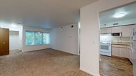 Located at 1703 Cresthill Ave in Royal Oak, Michigan, this single-floor unit offers a straightforward, functional layout with a clean and neutral aesthetic throughout. The open living and dining area is spacious, featuring wall-to-wall carpet and crisp white walls that create a bright, airy atmosphere. A large window with vertical blinds allows generous natural light to fill the main living space, while a chandelier overhead adds a modest decorative touch to the dining area. A half-wall partition elegantly defines the transition between the living and dining zones.

The kitchen is positioned adjacent to the main living area and is accessible via an open pass-through design. It features light wood laminate cabinetry, laminate countertops, a double-basin sink, and white appliances including a range, dishwasher, and refrigerator. The kitchen floor is finished in wood-look vinyl, offering a practical contrast to the carpeted areas.

The bedrooms are carpeted and well-proportioned, each with windows that bring in natural light and views of surrounding greenery. Closet space is present in the primary bedroom.

Two bathrooms serve the unit. One includes a vanity with light wood cabinetry, a tub/shower combination, and white tile flooring. The second bathroom features a stand-alone shower with sliding glass doors, a matching vanity, and the same clean tile flooring, offering practical functionality throughout.