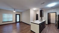 Located at 406 Noel Ln in Smyrna, Tennessee, this single-story residence presents a well-designed, open-concept floor plan with a cohesive contemporary aesthetic. The living area is finished with rich, wood-style plank flooring and neutral-toned walls, creating a clean and inviting atmosphere. A ceiling fan provides comfort overhead, while a large window and glass-paneled entry door allow natural light to fill the space.

The kitchen is a standout feature, boasting dark espresso cabinetry with brushed hardware, white quartz countertops, and a full suite of stainless steel appliances including a refrigerator, electric range, microwave, and dishwasher. A peninsula with an integrated sink and additional seating potential connects the kitchen seamlessly to the living area, making it well-suited for everyday use and entertaining.

The bedroom is carpeted for comfort, offering a quiet retreat off the main living corridor. The bathroom features wood-style flooring consistent with the rest of the unit, dark vanity cabinetry with a white countertop, and a tub-shower combination with a curtain surround. Throughout the residence, dark-framed interior doors and bold baseboards provide sharp contrast against the light walls, reinforcing the modern design sensibility.