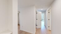 This well-appointed 3-bedroom, 1-bathroom residence delivers a clean, modern aesthetic across a single floor of generously proportioned living space. The open-plan kitchen and living area serves as the heart of the home, anchored by floor-to-ceiling windows that flood the space with natural light and frame expansive urban views. The kitchen features a sleek design with two-tone cabinetry — warm light wood lower cabinets paired with charcoal upper units — complemented by a white subway tile backsplash, quartz countertops, stainless steel appliances, and light hardwood-style flooring that carries throughout the entire residence. The spacious living area benefits from oversized windows on two walls, creating a bright and airy atmosphere with sweeping city vistas. Each of the three bedrooms is comfortably sized, including a primary bedroom with its own closet, and all feature large windows with urban views. Three dedicated closets provide excellent storage throughout. The bathroom is finished in a clean, modern style with a wood-accented vanity, a large mirror, and a full tub-shower combination. A well-organized hallway with louvered closet doors connects all areas of the home, completing this thoughtfully designed urban residence.