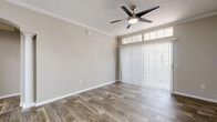 This thoughtfully designed 1-bedroom, 1-bathroom residence offers a comfortable and functional single-floor layout. The living room is a welcoming space, highlighted by wood-look plank flooring, crown molding, a ceiling fan with integrated lighting, and a large sliding glass door topped with transom windows that allows natural light to fill the room. Vertical blinds provide privacy and light control.

The galley-style kitchen is clean and contemporary, featuring white shaker cabinetry with modern hardware, light quartz countertops, a subway tile backsplash, and a full suite of stainless steel appliances including an electric range, microwave, dishwasher, and refrigerator. The wood-look flooring continues seamlessly throughout the kitchen.

The bedroom offers a cozy retreat with plush carpeting and access to a dedicated walk-in closet outfitted with wire shelving and hanging rods for organized storage. The bathroom is well-equipped with a tub-shower combination featuring white tile surround, a quartz-topped vanity, and wood-look flooring. A hallway connects the living areas to the private spaces, completing this efficiently planned and move-in ready home.