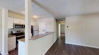 Located at 1373 Ivy Ln in Naperville, IL, this single-floor residence offers a well-designed layout with a blend of functional spaces and comfortable finishes. The open-concept living and kitchen area serves as the heart of the home, where a peninsula countertop with a built-in sink creates a natural divide between the two spaces while maintaining a connected, airy feel. Dark hardwood flooring runs throughout the main living areas, adding warmth and continuity to the space.

The kitchen is equipped with stainless steel appliances, including a refrigerator, microwave, and range, complemented by white cabinetry that provides ample storage. The living room is highlighted by a striking black corner fireplace and a sliding glass door that opens to the outside, inviting natural light into the room. The front entryway features a classic paneled door with sidelights.

The bedroom is carpeted for added comfort and features a large window with views of surrounding greenery, along with a closet offering convenient built-in shelving and hanging space. The bathroom is clean and functional, with a single-sink vanity with stone-look countertops, a tub-shower combination, and chrome fixtures throughout. Textured ceilings are present throughout the residence.
