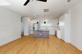 Located at 411 Charles Ave in Charlotte's vibrant 28205 corridor, this contemporary 4-story townhome offers a thoughtfully designed layout across multiple levels. The ground floor features an attached garage with concrete flooring, an electrical panel, and utility connections, providing practical entry-level functionality. The main living floor showcases a bright, open-concept kitchen and living room with warm light wood flooring throughout, crisp white walls, and a ceiling fan that enhances airflow. The kitchen is a standout feature, equipped with white shaker cabinetry, a bold center island with dark countertops, stainless steel appliances including a French-door refrigerator and range, white subway tile backsplash, and stylish black pendant lighting. Large windows invite abundant natural light into every level. The two bedrooms each feature light hardwood floors, ceiling fans, and generous windows with outdoor views. The five bathrooms are finished with clean white walls, matte black hardware accents, and distinctive geometric-patterned tile flooring. A dedicated laundry room houses a full-size Whirlpool washer and dryer. The home also includes a balcony, two closets, and multiple staircase connections between floors, offering a well-organized and modern urban living experience.