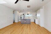 Located at 411 Charles Ave in Charlotte's vibrant 28205 corridor, this contemporary 4-story townhome offers a thoughtfully designed layout across multiple levels. The ground floor features an attached garage with concrete flooring, an electrical panel, and utility connections, providing practical entry-level functionality. The main living floor showcases a bright, open-concept kitchen and living room with warm light wood flooring throughout, crisp white walls, and a ceiling fan that enhances airflow. The kitchen is a standout feature, equipped with white shaker cabinetry, a bold center island with dark countertops, stainless steel appliances including a French-door refrigerator and range, white subway tile backsplash, and stylish black pendant lighting. Large windows invite abundant natural light into every level. The two bedrooms each feature light hardwood floors, ceiling fans, and generous windows with outdoor views. The five bathrooms are finished with clean white walls, matte black hardware accents, and distinctive geometric-patterned tile flooring. A dedicated laundry room houses a full-size Whirlpool washer and dryer. The home also includes a balcony, two closets, and multiple staircase connections between floors, offering a well-organized and modern urban living experience.