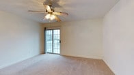 This single-floor, two-bedroom space on Dunlop offers a practical and comfortable layout designed for everyday living. The kitchen is a standout feature, equipped with stainless steel appliances including a refrigerator and electric range, complemented by warm oak cabinetry and granite-style countertops. A peninsula provides additional counter space and serves as a natural divider between the kitchen and the adjoining carpeted living area, creating an open, connected feel. Overhead fluorescent lighting keeps the kitchen well-lit, while the cabinetry offers generous storage throughout.

The living area is generously sized, featuring soft wall-to-wall carpeting and a ceiling fan with integrated lighting. A sliding glass door fills the room with natural light and provides direct access to an outdoor area, making the space feel open and airy. The textured ceiling adds subtle visual character throughout.

A hallway connects the main living areas to the bedrooms, with glimpses of additional rooms visible in the background. The overall aesthetic is clean and neutral, with a warm color palette of beige tones and natural wood finishes that create an inviting, move-in-ready environment.