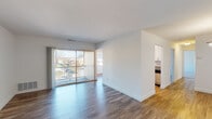 This single-floor residence offers a well-organized layout with a clean, modern aesthetic throughout. The living area is spacious and filled with natural light, courtesy of large sliding glass doors that open to a private balcony with outdoor views. Dark hardwood-style flooring runs through the living and dining areas, creating a warm contrast against the bright white walls.

Adjacent to the living space, a dedicated dining area features lighter hardwood-style flooring and a pendant light fixture, connecting seamlessly to the galley-style kitchen. The kitchen is well-appointed with white cabinetry, granite countertops, subway tile backsplash, and a full suite of stainless steel appliances, including a gas range, built-in microwave, dishwasher, and refrigerator.

The bedrooms are carpeted for comfort and include ceiling fans, natural light from windows, and closet space. One bedroom features a walk-in closet with built-in shelving, providing generous storage. The bathroom is finished in a clean, all-white palette with a tiled shower-tub combination, a single-sink vanity with white cabinetry, and a large mirror. The overall ambiance is bright, neutral, and move-in ready.