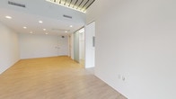 Located along Euclid Avenue in Cleveland's University Circle neighborhood, this single-floor space offers a clean, contemporary design with an open and flexible layout. The main living area is expansive and filled with natural light streaming through large windows and a glass-panel entry door, creating an airy and welcoming atmosphere. Light wood-tone flooring runs throughout the space, complementing the crisp white walls and contributing to a bright, minimalist aesthetic.

A standout architectural feature is the striking slatted ceiling detail near the entry, which adds a modern industrial character to the otherwise clean interior. Recessed lighting is thoughtfully distributed across the ceiling, providing even, consistent illumination throughout. The varied ceiling heights add visual interest and a sense of dimension to the open areas.

A frosted glass sliding door leads to a dedicated storage or closet area, offering practical organization solutions while maintaining the sleek design language of the space. The kitchen is equipped with white cabinetry and modern appliances, providing a functional and polished cooking environment.

The bathroom features floor-to-ceiling white mosaic tile in the tub and shower surround, complemented by small-format mosaic tile flooring, chrome fixtures, and a clean, spa-like finish. Overall, the space presents a well-designed, move-in-ready environment suited for a variety of uses.