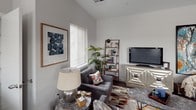 This single-floor residence offers a thoughtfully designed layout that balances functionality with contemporary style. The kitchen is a standout feature, showcasing dark wood-grain cabinetry paired with bright white quartz countertops and a matching island that provides additional workspace and seating. Stainless steel appliances, including a gas range, built-in microwave, and refrigerator, complete the modern aesthetic, while dark hardwood flooring and natural light from multiple windows enhance the overall appeal.

The living area is generously proportioned, offering ample space for comfortable seating arrangements. Vaulted ceilings add a sense of openness, and a large window allows natural light to fill the room, creating a welcoming ambiance.

The two bedrooms are carpeted for comfort and feature neutral wall tones and windows with outdoor views. One bedroom includes access to a walk-in closet with wire shelving and a direct connection to a full bathroom.

The primary bathroom is finished with wood-grain cabinetry, dual sinks set in a white quartz vanity, a large mirror with overhead lighting, and a glass-enclosed shower, delivering a clean and polished aesthetic throughout.
