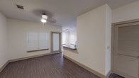 Located at 12325 Shadow Creek Pkwy in Pearland, Texas, this single-floor residence offers a thoughtfully designed open-concept layout that seamlessly connects the living and kitchen areas. The living space features rich wood-look flooring, neutral walls, a ceiling fan with light fixture, and multiple windows with blinds that allow natural light to fill the room. A private exterior door provides convenient access from the living area.

The kitchen is a standout feature, showcasing dark espresso cabinetry that extends to the ceiling, granite countertops, and a suite of stainless steel appliances including a French door refrigerator with ice maker, an electric range, and an over-the-range microwave. A peninsula counter with a granite overhang and sink opens toward the living area, enhancing the open-concept feel.

The bedroom is generously sized with plush wall-to-wall carpeting, a ceiling fan, and a doorway leading directly into a walk-in closet with built-in shelving. The bathroom is finished with large-format tile flooring, a long dual-sink vanity topped with granite, dark cabinetry, framed mirrors, and a tub-shower combination, offering ample functionality and a clean, modern aesthetic throughout.