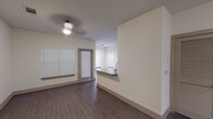 Located at 12325 Shadow Creek Pkwy in Pearland, Texas, this single-floor residence offers a thoughtfully designed open-concept layout that seamlessly connects the living and kitchen areas. The living space features rich wood-look flooring, neutral walls, a ceiling fan with light fixture, and multiple windows with blinds that allow natural light to fill the room. A private exterior door provides convenient access from the living area.

The kitchen is a standout feature, showcasing dark espresso cabinetry that extends to the ceiling, granite countertops, and a suite of stainless steel appliances including a French door refrigerator with ice maker, an electric range, and an over-the-range microwave. A peninsula counter with a granite overhang and sink opens toward the living area, enhancing the open-concept feel.

The bedroom is generously sized with plush wall-to-wall carpeting, a ceiling fan, and a doorway leading directly into a walk-in closet with built-in shelving. The bathroom is finished with large-format tile flooring, a long dual-sink vanity topped with granite, dark cabinetry, framed mirrors, and a tub-shower combination, offering ample functionality and a clean, modern aesthetic throughout.