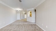 Located in Largo, FL, this well-appointed single-story home offers a thoughtfully designed layout across two bedrooms, one bathroom, a living room, kitchen, laundry room, hallway, and two closets. The kitchen is a functional highlight, featuring white shaker cabinetry, granite-look countertops, a tile backsplash, black appliances including a range and built-in microwave, and light wood-look luxury vinyl flooring that creates a clean, contemporary feel. The living room is bright and welcoming, adorned with crown molding, a ceiling fan, and a charming arched window nook that floods the space with natural light. Both bedrooms are generously sized with plush carpeting, ceiling fans, and walk-in closets equipped with wire shelving for ample storage. The primary bedroom is notably spacious, offering room for a full furniture arrangement. The bathroom is finished with a white vanity with granite countertops, and a full tub-shower combo. A dedicated in-unit laundry room adds everyday convenience. Throughout, neutral tones, vaulted ceilings in select areas, and consistent finishes create a cohesive and comfortable living environment.
