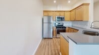 Located at 1618 Bellevue Ave in Seattle's vibrant Capitol Hill neighborhood, this one-bedroom, one-bathroom unit offers a well-designed layout with efficient use of space throughout. Light-toned hardwood-style flooring runs continuously through the unit, creating a cohesive and clean aesthetic against crisp white walls.

The kitchen is equipped with warm-toned wood cabinetry, stainless steel appliances including a gas range, microwave, and refrigerator, and a gray countertop that extends to a peninsula, seamlessly connecting to the combined dining and living area. A hallway leads from the entry past two closets, providing generous storage. The living area is brightened by a large window and sliding glass door opening to a private balcony with city views.

The bedroom is a well-proportioned room featuring a window with views of the Seattle skyline, hardwood-style flooring, and a spacious sliding-door closet. The bathroom includes a full tub-shower combo with white tile surround and chrome fixtures. An in-unit laundry area adds everyday convenience. Recessed lighting throughout enhances the bright, modern feel of this thoughtfully designed urban home.