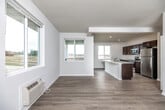 This single-floor space offers a clean, contemporary design characterized by neutral white and gray walls, light hardwood-style flooring, and an abundance of natural light drawn in through multiple windows. The open-concept layout seamlessly connects the living area to the kitchen, creating a spacious, airy feel. The kitchen is well-appointed with rich dark-stained cabinetry, white countertops, a central island with a double sink, and a full suite of stainless steel appliances including a range, microwave, and refrigerator. Recessed lighting throughout the kitchen adds a polished finish.

The living area is generously proportioned, featuring wall-unit climate control and large windows that frame outdoor views. Bedrooms vary in finish, with some featuring soft carpeting, ceiling fans, wall-unit HVAC, and ample closet space with built-in shelving. One bedroom showcases light hardwood flooring and recessed lighting for a more refined look. The bathroom includes a dark wood vanity with a white countertop, hardwood-style flooring, and brushed nickel fixtures and grab bars. Overall, the space presents a fresh, move-in-ready environment with consistent, modern finishes.