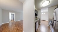 Located on Longtree Court in Schaumburg, Illinois, this well-appointed one-bedroom, one-bathroom residence offers a thoughtfully designed single-floor layout. Warm hardwood-style flooring flows throughout the main living areas, creating a cohesive and inviting atmosphere. The spacious living room is anchored by large sliding glass doors fitted with vertical blinds, bathing the space in natural light and providing direct access to the outdoors. A classic chandelier adds a refined touch to the dining area just off the living room. The kitchen features dark cabinetry, light quartz-style countertops, a stainless steel double-basin sink with a brushed nickel faucet, a dishwasher, and a sleek subway tile backsplash. The bedroom is carpeted for comfort and includes a generous closet, a window with outdoor views, and a wall-mounted air conditioning unit alongside baseboard heating. The bathroom is neatly arranged with a granite-topped vanity, wood-look flooring, and a separate tub-shower combination. A welcoming entrance completes the layout. The unit's neutral palette, practical finishes, and functional design make it a comfortable and move-in-ready home in the heart of Schaumburg.