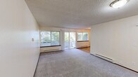 Located at 3015 N Pearl St in Tacoma, WA, this two-bedroom, one-bathroom unit offers a practical and well-organized single-floor layout. The spacious living room is a standout feature, with large sliding glass doors and wide windows that invite abundant natural light and provide views of the surrounding greenery. Baseboard heating and plush carpeting throughout create a comfortable atmosphere. The galley-style kitchen is efficiently designed with light wood cabinetry — including glass-front upper cabinets — laminate countertops, a stainless steel refrigerator, electric range, and tile flooring, making the most of the available space. The combined dining area flows seamlessly from the kitchen. Both bedrooms are carpeted and feature windows with outdoor views, baseboard heating, and access to one of three closets for ample storage. The primary bedroom includes a dedicated closet with a hanging rod and an additional door for privacy. The full bathroom is clean and functional, featuring a vanity with warm wood cabinetry, a full tub-shower combination, tile flooring, and chrome fixtures. Throughout the unit, textured ceilings and neutral walls provide a versatile backdrop well-suited for a variety of interior styles.