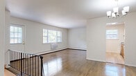 Located at 13 Vermeer Drive in South Amboy, NJ, this 2-bedroom, 1-bathroom home offers a practical and comfortable layout accessed via a staircase with rich wood-tread steps and dual dark wood handrails. The main living area is bright and open, showcasing gleaming hardwood floors and multiple windows that invite generous natural light. A chandelier adds a decorative touch to the dining area, which flows naturally from the living room. The kitchen features warm oak cabinetry, dark countertops, light vinyl plank flooring, a window above the sink, and white appliances including a range and refrigerator. Both bedrooms are comfortably sized, featuring hardwood floors, natural light from large windows, and ample closet space — with two closets visible in one bedroom. The full bathroom is finished with large-format beige stone-look wall tiles and a clean white soaking tub. Four closets throughout the home provide substantial storage. A private balcony off the main level overlooks a landscaped setting with mature trees, open lawn, and parking. The home's clean, neutral palette and well-maintained finishes create a bright and functional living environment.