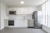 Located at 198 Walnut Ave in Toronto's vibrant Parkdale-West Queen West neighbourhood, this two-bedroom, one-bathroom unit offers a clean, modern interior designed with simplicity and functionality in mind. The open kitchen and living area features light grey tile flooring, crisp white cabinetry, stainless steel appliances including a built-in oven, microwave, dishwasher, and refrigerator, complemented by ample counter space and recessed lighting overhead. The living area transitions seamlessly from the kitchen, benefiting from a large window that fills the space with natural light. Both bedrooms feature warm light hardwood flooring, bright white walls, and expansive floor-to-ceiling windows that frame views of the surrounding neighbourhood, including a notable heritage brick building. The primary bedroom includes mirrored sliding closet doors that enhance the sense of space. The bathroom is finished with large-format grey wall tiles surrounding a full soaker tub with an overhead shower. Baseboard heating runs throughout the unit, and the overall aesthetic is consistent — minimal, bright, and well-maintained — making this a comfortable and practical urban residence.