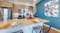 Located at 315 Edith Ave in Nashville, Tennessee, Unit 308 is a thoughtfully designed single-floor residence that blends contemporary style with everyday functionality. The open-concept kitchen serves as a visual centerpiece, featuring granite countertops, a spacious island with bar seating, gray cabinetry, stainless steel appliances including a range and built-in microwave, subway tile backsplash, and wood-look flooring. A bold teal accent wall adds a striking pop of color, complemented by modern pendant lighting overhead.

The living area offers a welcoming atmosphere with natural light streaming through a large window dressed in warm, sheer curtains. Wood-look flooring continues through this space, which also includes a dedicated nook with a sleek wall-mounted shelving unit and a comfortable accent chair — ideal as a reading or work area.

The bedroom is carpeted and generously sized, with windows providing ample natural light, a ceiling fan, and convenient access to both the walk-in closet and in-unit laundry. The walk-in closet features wire shelving for flexible storage. The bathroom is clean and bright, finished with white tile and a glass-enclosed standing shower with brushed nickel fixtures. Throughout, the unit maintains a cohesive, modern aesthetic with neutral tones and quality finishes.