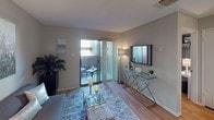 Located at 6701 Everhart Rd. in Corpus Christi, Texas, this single-floor unit offers a thoughtfully laid-out interior with consistent neutral tones, wood-style flooring, and a textured ceiling throughout. The living area is bright and inviting, anchored by a sliding glass door that opens to a private outdoor patio, allowing natural light to flow into the space. The kitchen is efficiently designed with white cabinetry, light countertops, a double stainless steel sink, black appliances including a refrigerator and range, and track lighting overhead — offering both functionality and a clean aesthetic. The bedroom is a comfortable retreat featuring a ceiling fan, a wide sliding-door closet with generous storage, and a window with blinds that lets in soft natural light. A second bedroom or flex space connects to the rest of the unit via a hallway, adding versatility to the floor plan. The bathroom is elongated and well-equipped, featuring a dual-sink vanity with white cabinetry, a large mirror, and a shower with a decorative curtain. Throughout the unit, the soft gray wall palette, wood-style flooring, and consistent finishes create a cohesive and welcoming atmosphere.