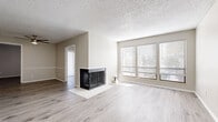 Located at 505 N Rock Rd in Wichita, Kansas, this single-floor unit offers a well-designed layout that balances comfort and functionality. The living area is a standout space, anchored by a corner fireplace with a classic tile hearth and framed by a large bank of windows fitted with horizontal blinds, allowing ample natural light to fill the room. Light-toned wood-look flooring runs throughout the main living spaces, creating a clean, cohesive aesthetic, while a textured popcorn ceiling adds a classic touch overhead. A sliding glass door with vertical blinds opens to an outdoor patio, providing a seamless connection to the exterior. The open-concept design connects the living area to a dining space and a galley-style kitchen, which is equipped with white cabinetry, dark speckled countertops, black appliances including a refrigerator and electric range, and a double-basin sink. A pass-through counter visually links the kitchen to the adjacent living and dining areas. The bedroom features darker wood-look flooring and an open closet with a hanging rod, offering practical storage. The bathroom includes a tub-shower combination, white cabinetry with dark countertops, and wood-look flooring, maintaining the home's consistent design language throughout.