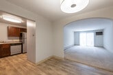 This single-floor residence offers a thoughtfully designed layout that balances comfort and functionality. The entry foyer features wood-look flooring and flows through a distinctive arched doorway into the carpeted living room, which is bathed in natural light from a large sliding glass door that opens to an outdoor view. Baseboard heating runs throughout the space, ensuring year-round comfort.

The kitchen is well-equipped with rich dark cherry cabinetry, granite-style countertops, stainless steel appliances including a refrigerator and dishwasher, an electric range with overhead ventilation, and a stainless steel sink. Wood-look tile flooring completes the kitchen's clean, polished aesthetic.

The bedrooms are comfortably sized, each featuring neutral wall-to-wall carpeting, baseboard heating, and windows with blinds that allow natural light and outdoor views. The rooms offer a calm, airy atmosphere with neutral tones throughout.

The bathroom is finished with wood-look flooring and includes a full tub and shower combination fitted with chrome fixtures and a safety grab bar, along with a toilet and vanity. The overall design of the space is clean and neutral, with consistent finishes that create a cohesive and move-in-ready environment.