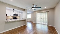 Located in Austin's desirable 78704 zip code, this 1-bedroom, 1-bathroom unit offers a thoughtfully designed layout that maximizes every inch of its comfortable footprint. The open-concept living and kitchen area serves as the heart of the home, where rich hardwood-style flooring runs throughout, reflecting natural light that pours in through a full-width sliding glass door. The door opens to an outdoor view framed by lush greenery, while vertical blinds provide privacy and light control. A ceiling fan with integrated lighting completes the airy living space. The kitchen is a standout feature, boasting crisp white cabinetry, granite-style countertops, stainless steel appliances including a range, microwave, and refrigerator, and a striking chevron-patterned tile backsplash. A peninsula counter with pendant lighting creates a natural divide between the kitchen and living area. The bedroom offers plush carpeting, a ceiling fan, natural light from a window with blinds, and a full-width closet with modern sliding mirrored panel doors. The bathroom is clean and contemporary, featuring white subway tile surrounding the tub-shower combo, white cabinetry with matte black hardware, a granite-topped vanity, and hardwood-style flooring. Neutral tones throughout create a cohesive, move-in-ready atmosphere.