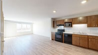 Located on Station Street in Big Lake, Minnesota, this one-bedroom, one-bathroom unit offers a well-organized single-floor layout designed for comfortable everyday living. The open-concept main area seamlessly connects the kitchen and living room, both finished with light wood-style plank flooring that lends a clean, modern aesthetic throughout.

The kitchen is equipped with warm-toned wood cabinetry offering ample upper and lower storage, light countertops, a double-basin stainless steel sink, and a full suite of black appliances including a range, dishwasher, microwave, and refrigerator. A ventilation hood above the range and an under-cabinet layout make the space both practical and efficient.

The living room is bright and open, benefiting from a large window that brings in natural light and offers views of the surrounding Big Lake landscape. An exposed ductwork detail adds an industrial touch to the otherwise clean, neutral interior.

The bedroom is generously sized, featuring plush carpeting, a large window with scenic outdoor views, and a dedicated closet for storage. The bathroom is well-appointed with warm wood vanity cabinetry, a white countertop, a large mirror, and a full tub-shower combination. Neutral tones and clean finishes carry throughout, creating a cohesive and move-in-ready atmosphere.