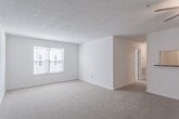 Located at 100 Bridgeport Cove Dr in Hampton, Virginia, this single-floor residence offers a clean, neutral aesthetic throughout. The open living area is generously proportioned, featuring soft wall-to-wall carpeting, a ceiling fan, and a large window that invites an abundance of natural light, creating a bright and airy atmosphere. A pass-through opening connects the living space to the kitchen, which is well-equipped with warm wood cabinetry, stone-toned countertops, a full-size refrigerator, and a range with a built-in overhead vent — all set atop durable hardwood-style flooring. The bedrooms are comfortably sized and carpeted, each featuring windows with blinds for natural light and privacy. At least one bedroom includes a built-in closet with a rod and shelf for organized storage. Two full bathrooms are present, each outfitted with a tub/shower combination and hardwood-style flooring, offering functional and practical design. Throughout the unit, crisp white walls and consistent neutral finishes create a cohesive, move-in-ready environment. The thoughtful layout provides clear separation between living, sleeping, and utility areas, making this a well-organized and practical living space.